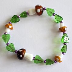 a bracelet with green leaves and white beads