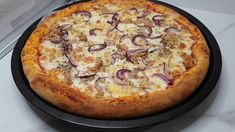 a pizza sitting on top of a pan covered in cheese and onions