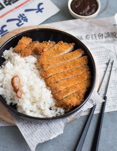 rice and meat in a bowl with chopsticks next to it on a table