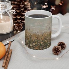 a coffee mug sitting on top of a table next to an orange and some pine cones