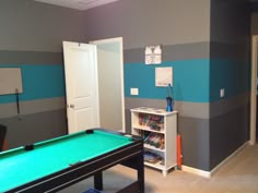 a pool table sitting in the middle of a room with blue and gray striped walls