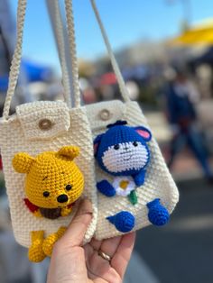 two crocheted purses are being held in the air by someone's hand