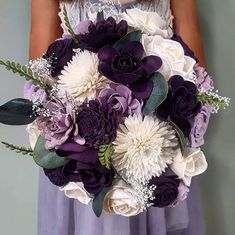 a bride holding a purple and white bouquet