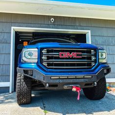 a blue gmc truck parked in front of a garage