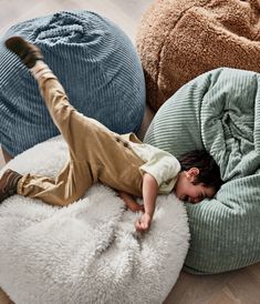 a young boy laying on top of a bean bag chair next to two large pillows