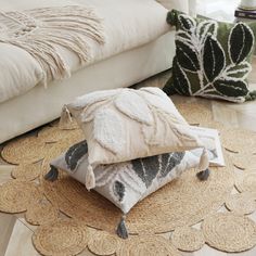 three pillows stacked on top of each other in front of a couch and coffee table