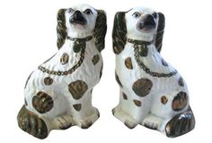 two ceramic dogs sitting next to each other on a white surface with chains around their necks