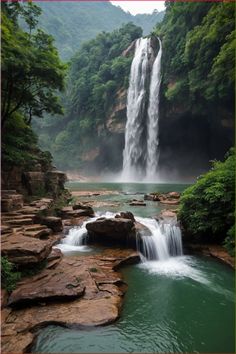 a large waterfall in the middle of a forest filled with rocks and water flowing down it's sides