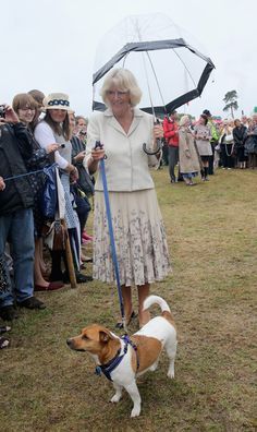 a woman holding an umbrella and walking her dog on a leash in front of a crowd