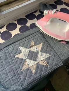 an ironing board sitting on top of a table next to a pink and white iron