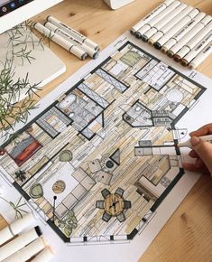 a person is drawing a floor plan on a piece of paper with markers and pencils