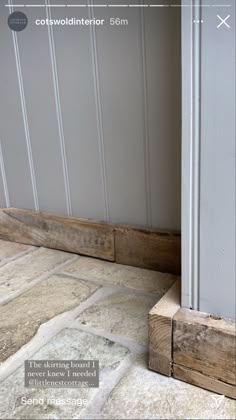 the corner of a room with a wooden door and tile flooring next to it