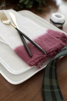 a place setting with two forks and a napkin on top of the plate, next to a fork and knife