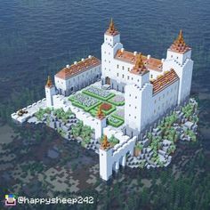 an aerial view of a white castle in the middle of water with trees and bushes around it