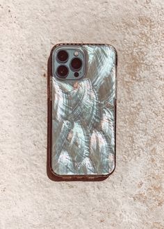 an iphone case sitting on top of a white wall with shells in it's back