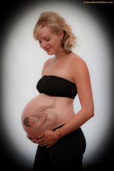 a pregnant woman in a black dress holding her belly