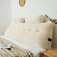 a bed with pillows and blankets on it in a room next to a wooden table