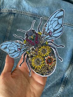 a person is holding up a sticker with a bee and flowers on it in their hand