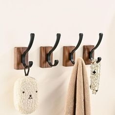 three hooks are hanging on the wall next to two towels and a teddy bear towel holder