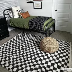 a black and white checkered rug with a green bed in the corner next to it