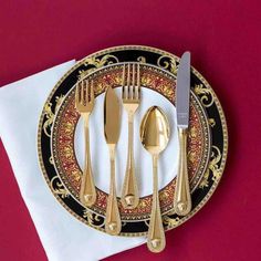 a black and gold plate with silverware on it, next to a white napkin