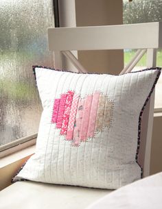 a pillow with two hearts on it sitting next to a window