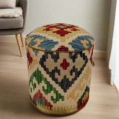 a multicolored ottoman sitting on top of a hard wood floor next to a chair