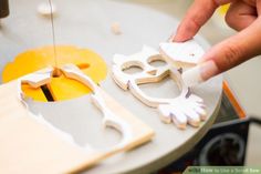 a person is cutting out some paper on a piece of wood with a small machine