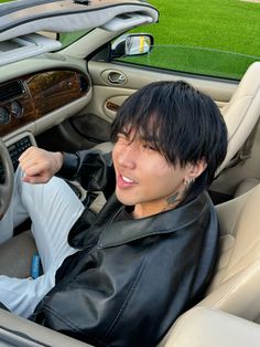 a man sitting in the driver's seat of a car with his hand on the steering wheel