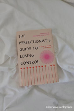 a book sitting on top of a white bed covered in sheets and pillows with the title, the perfectionoist's guide to losing control