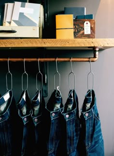 four pairs of jeans hanging from hooks on a shelf