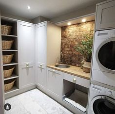 a washer and dryer in a small room with white cabinets, drawers and shelves