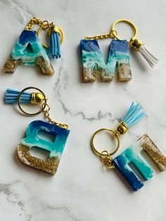 four different key chains with the letter e in them on a marble counter top,