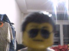 a blurry image of a man's face with sunglasses on and clothes hanging in the background