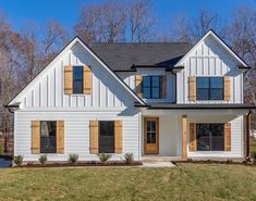 a large white house with wooden shutters on the front and side windows that have wood trim