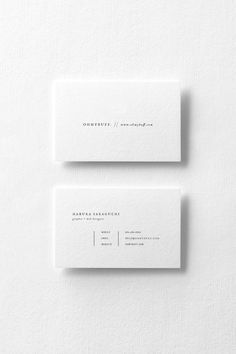 two white business cards sitting on top of each other