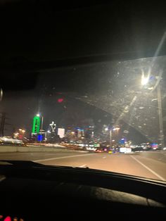 the view from inside a car at night with city lights in the backgroud