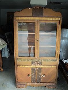 an old wooden china cabinet with glass doors and drawers in the middle of a room