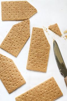 some crackers and a knife on a white surface with one cut in to pieces