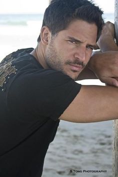 a man leaning against a pole on the beach