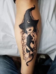 a woman's leg with a black and white tattoo design on her arm, holding a cat