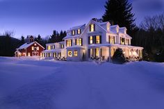 a large white house with lots of windows and lights on it's side in the snow