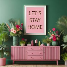 a pink dresser sitting in front of a green wall with potted plants on it