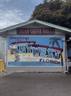 a sign advertising key west coffee on the side of a building with palm trees in the background