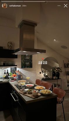 a kitchen with an island and stove in the center, surrounded by black cabinetry