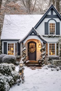 a house covered in snow with wreaths on the front door and lights hanging from the windows