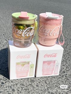 two pink and green coca - cola jars sitting on top of each other