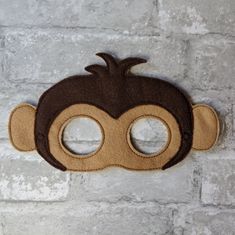 a monkey mask hanging on a brick wall with two holes in the middle for eyes