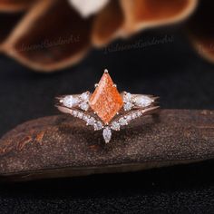 an orange and white diamond ring sitting on top of a rock