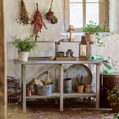 an old fashioned kitchen with pots and pans hanging on the wall next to potted plants